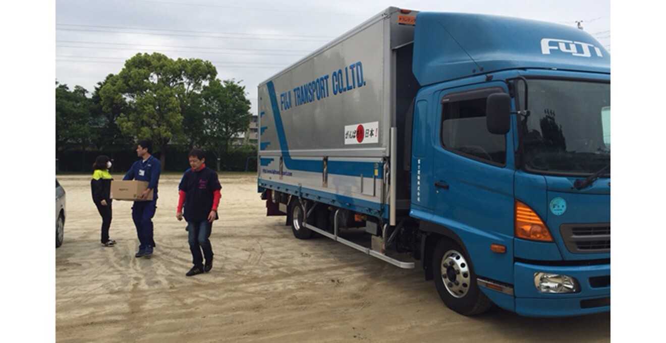 大型トラックからスタッフが支援物資を運ぶ写真