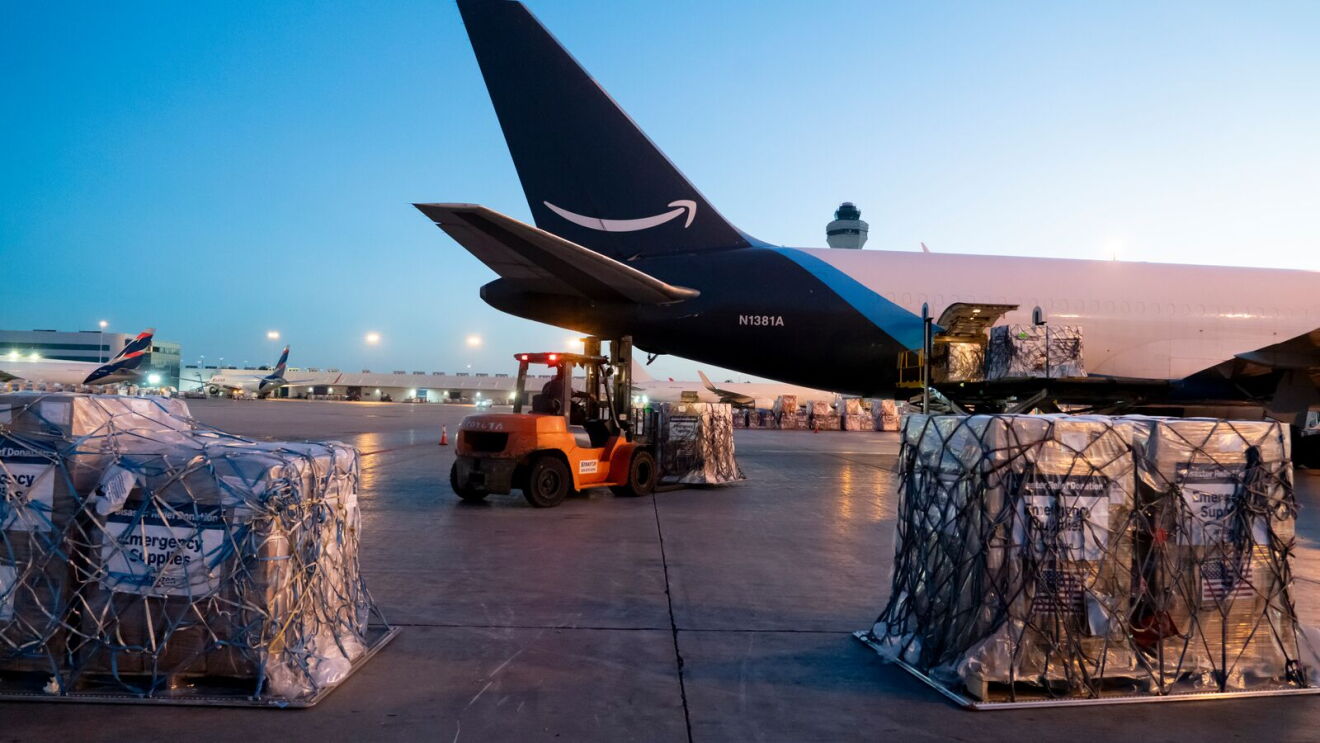 Amazon Prime cargo plane being loaded with palletized freight at airport during dawn or dusk