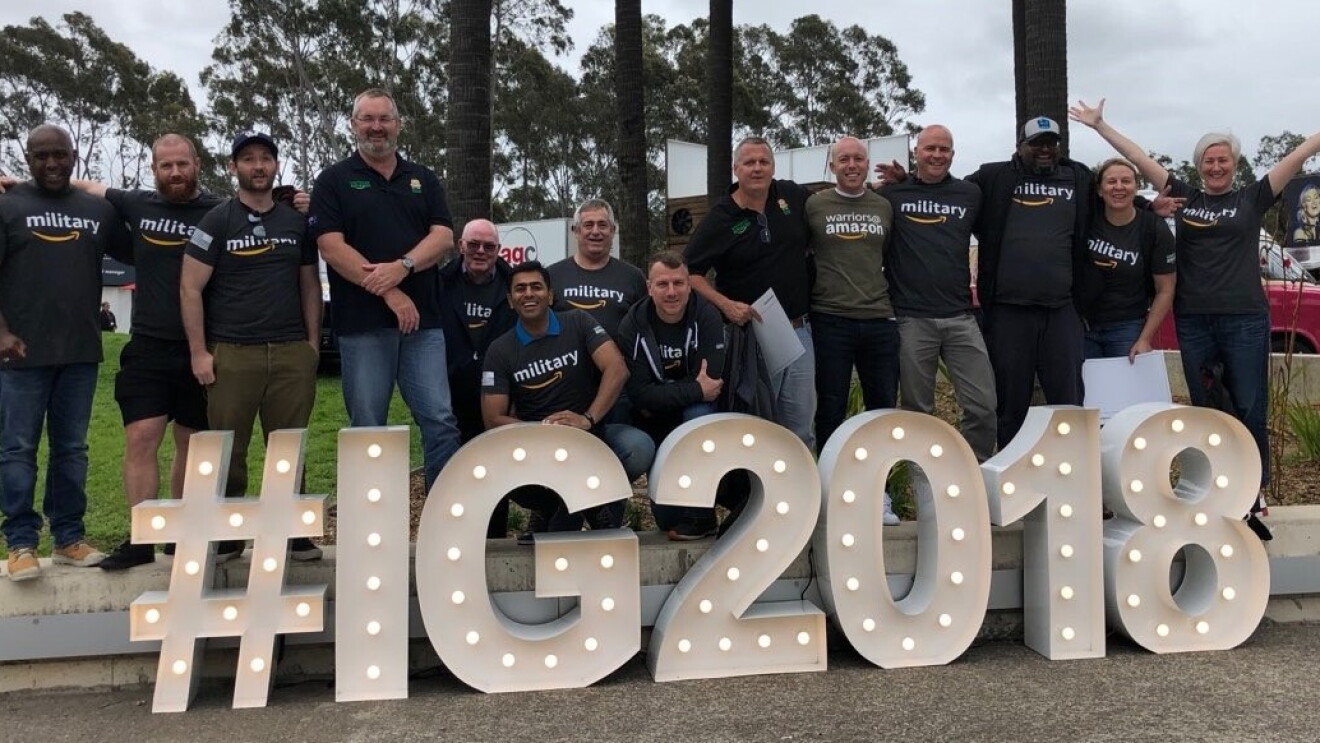 An image of a group of people standing in front of a light-up sign that says "#IG2018"