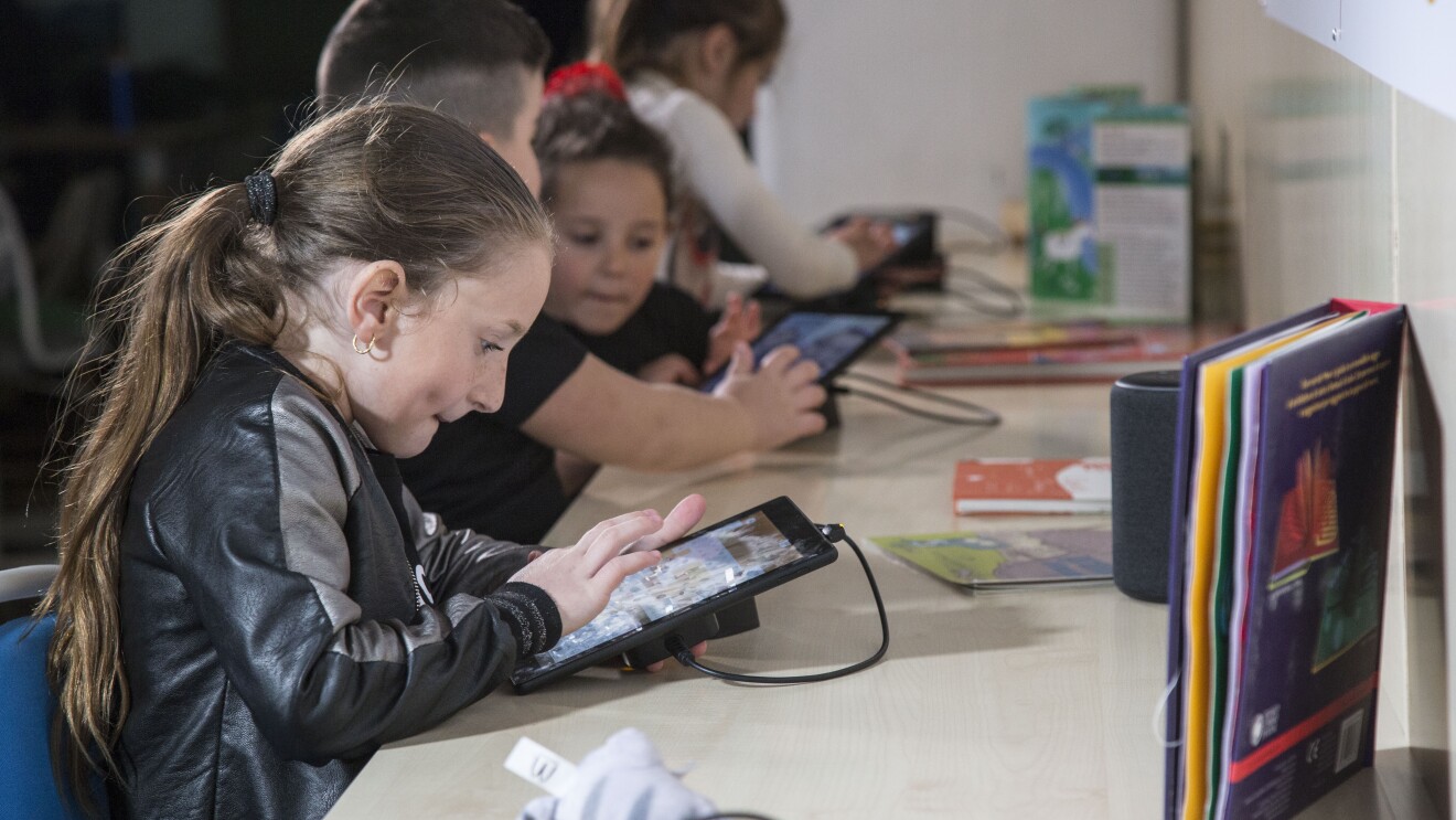 Bambini giocano con i tablet Fire messi a disposizione da Amazon per la sala multimediale della Biblioteca di Scampia