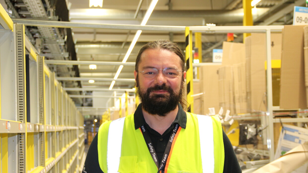 Amazon-Arbeitssicherheitsexperte Lucian Geiger mit gelber Weste im Logistikzentrum.