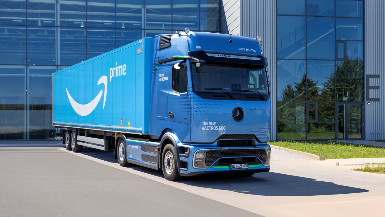 Sky blue coloured Mercedes Benz eActros 600 eHGV with Amazon trailer, parked in front of office building
