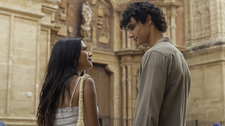 Man and woman look into each other's eyes standing in front of an ornate facade