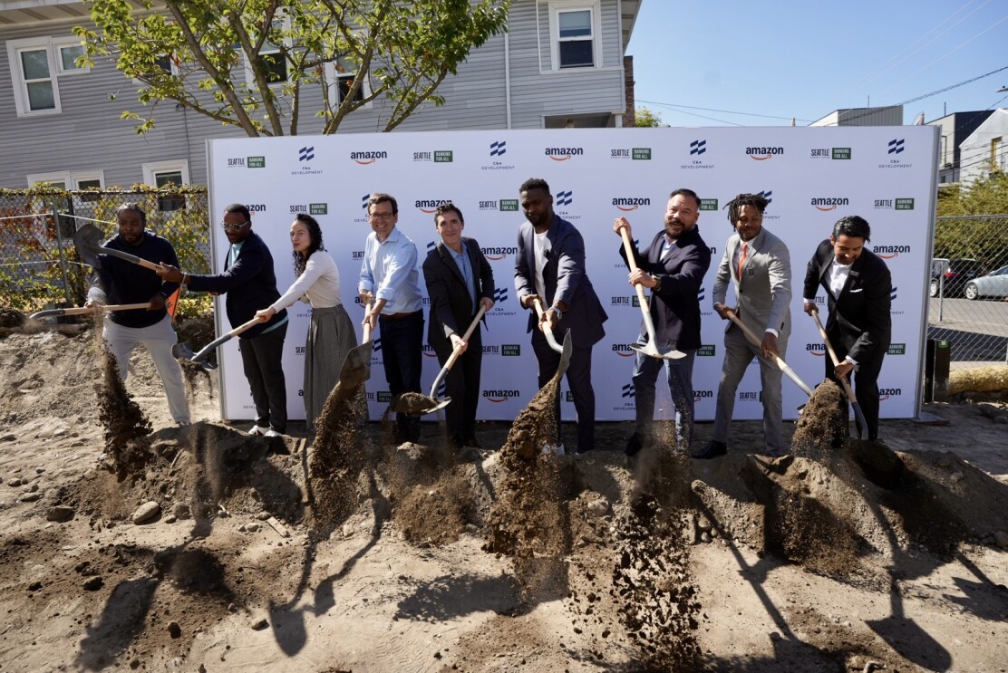 Business leaders and community representatives, including Governor Ferguson, Amazon VP Brian Huseman, and former Seahawk Cliff Avril, participating in groundbreaking ceremony with branded backdrop