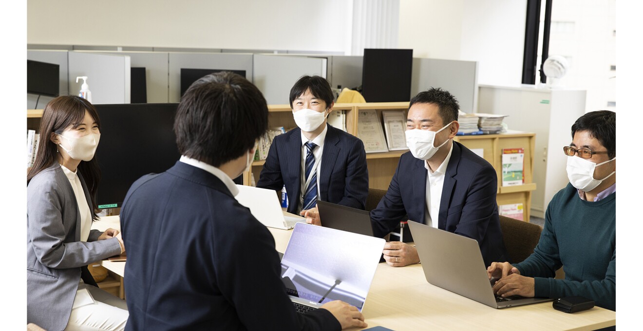 オフィスで和やかに社員が顔をあわせる写真