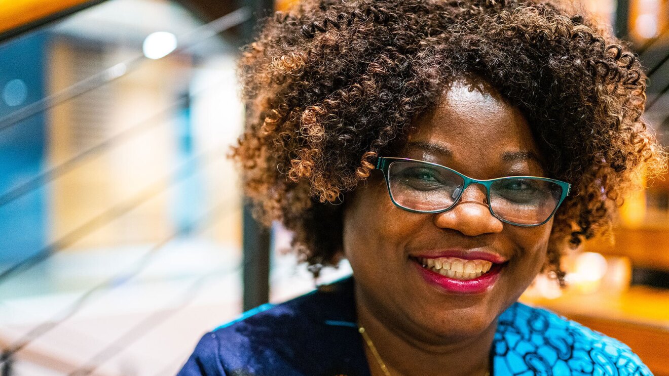 A headshot image of a woman smiling for a photo in front of steps in Amazon's office.