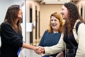 An image of Amazon's Senior Vice President of People Experience, Beth Galetti, shaking hands with employees in a hallway and smiling.