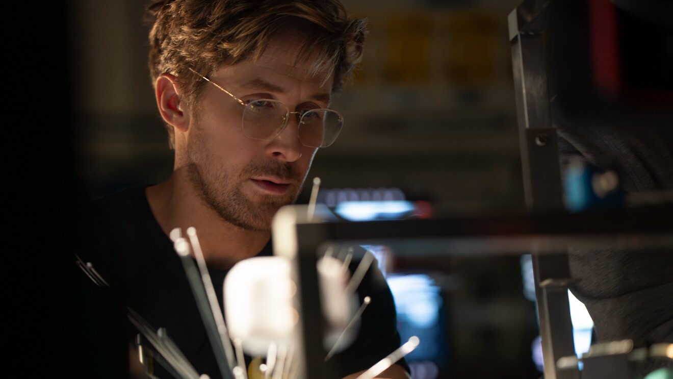 Scientist in glasses examining lab equipment in dim lighting