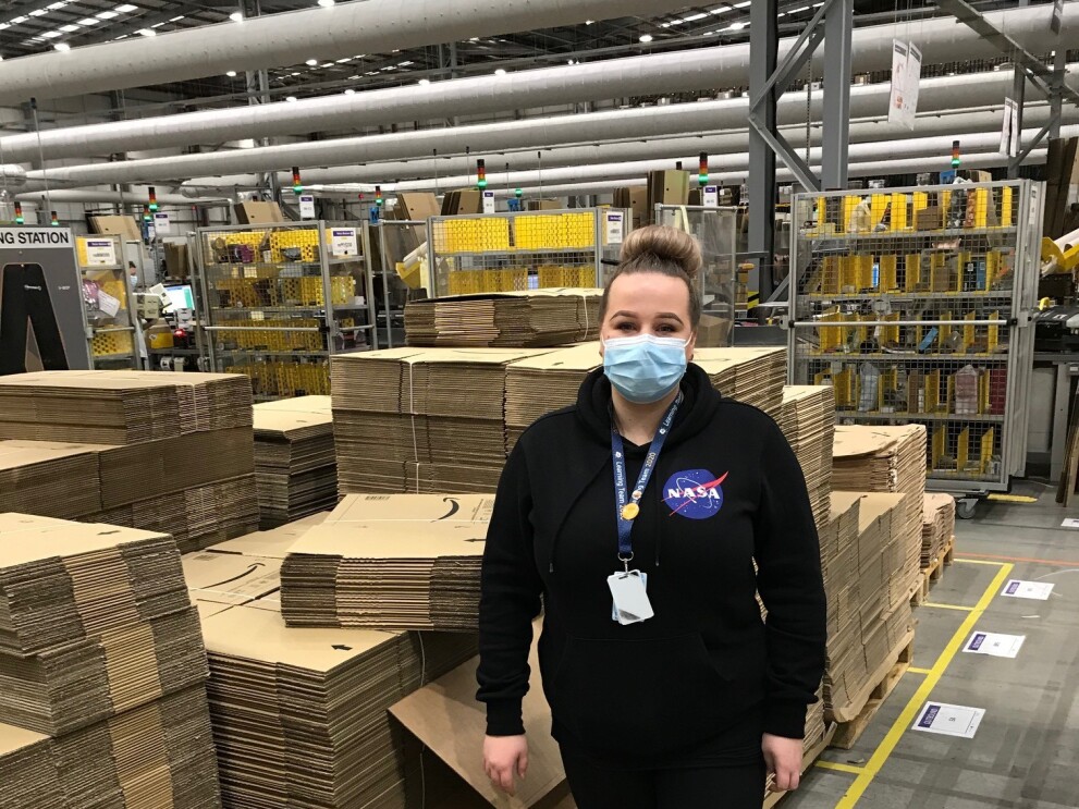Gintare Lapinaite, FC Lead, standing in a fulfilment centre next to lots of Amazon boxes.