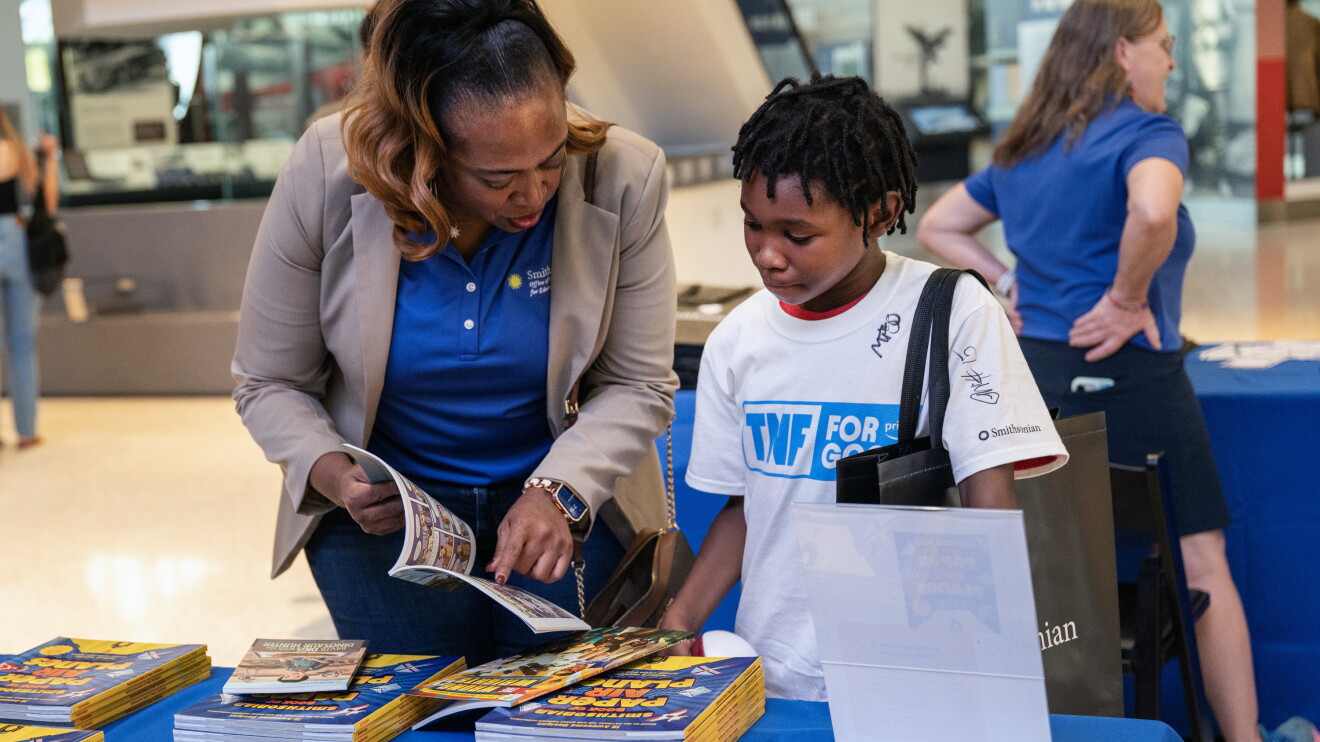 Adult and child browsing educational materials at Smithsonian event