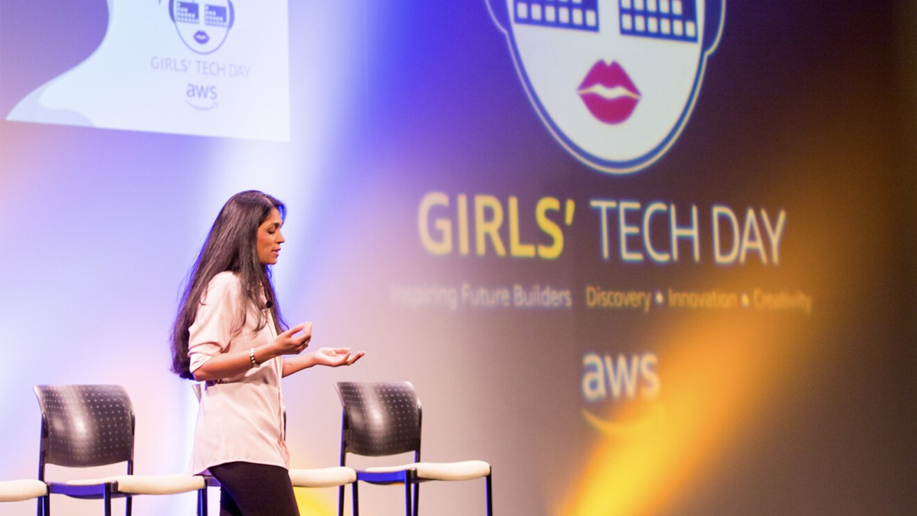 A woman stands on the stage and resents at Girls' Tech Day.