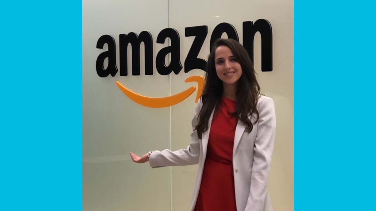 Juliana smiling while standing in front of a glass wall that says Amazon on it.