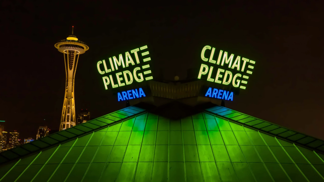 Primo piano del tetto della Climate Pledge Arena, con la scritta Climate Pledge Arena e sullo sfondo il needle di Seattle