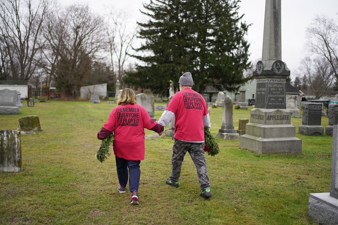 An image of Warriors@ members placing wreathes and flags on veterans' graves.
