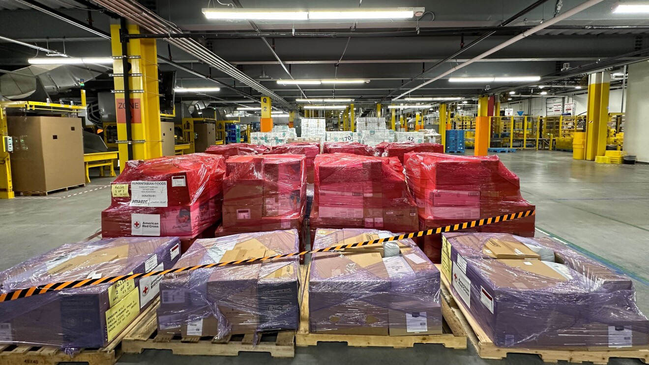 Warehouse storage area with stacked red and brown packages on pallets by DRbA for Hurricane Milton