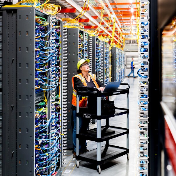 Modern server room with workers maintaining complex network infrastructure for data centers