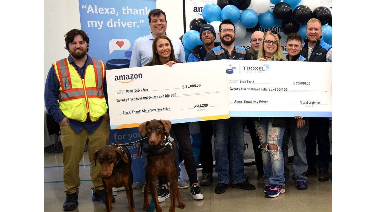 'Alexa, thank my driver' winners hold their winnings in a big check while they stand next to colleagues.