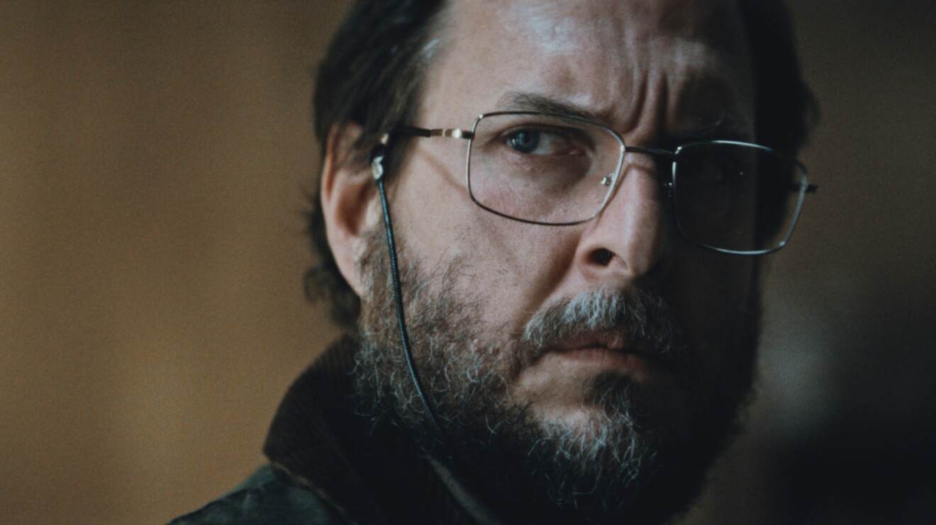 Image from the Los Iniciados movie of a man wearing glasses.