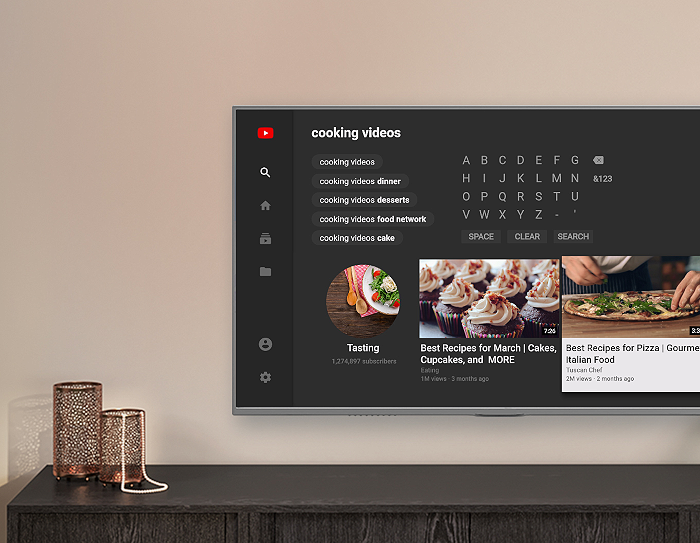 A wall-mounted television above a console shows the YouTube experience on Fire TV, with examples of cooking videos.