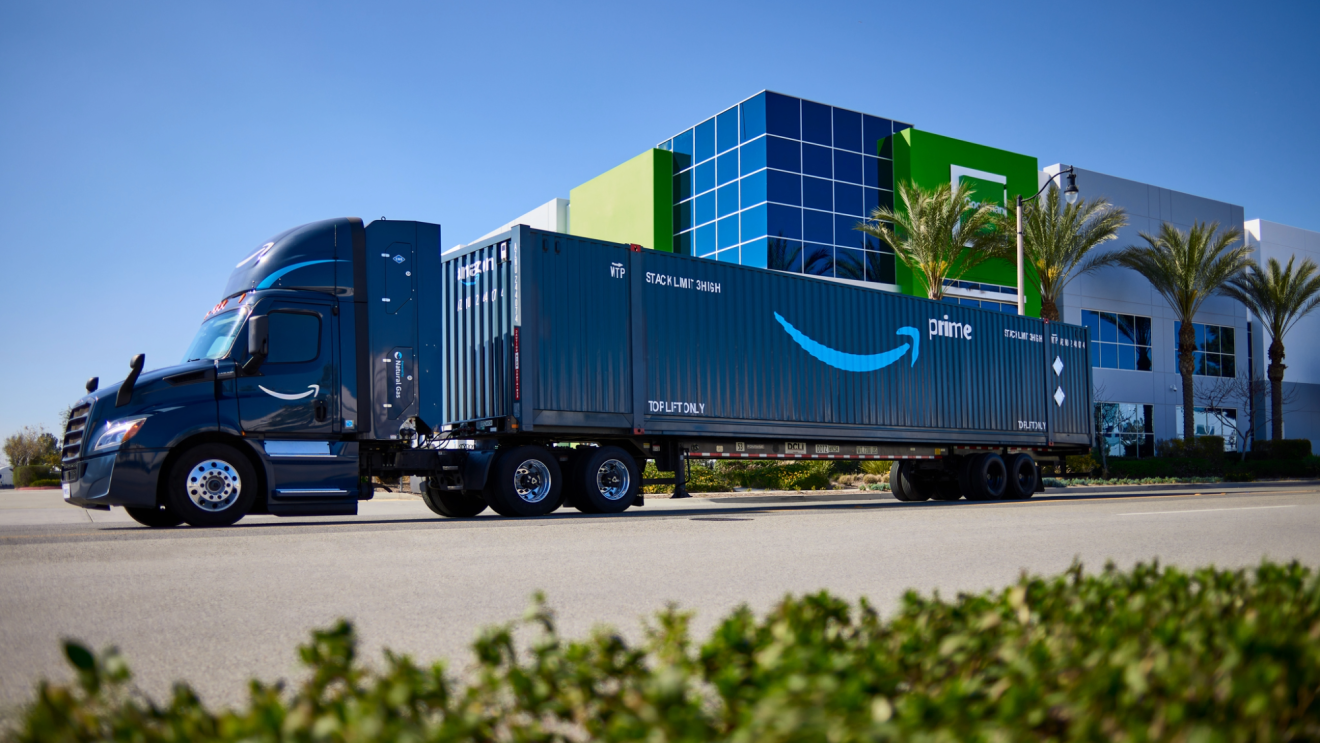 An Amazon Prime branded semi-truck and intermodal container parked outside a fulfillment center.
