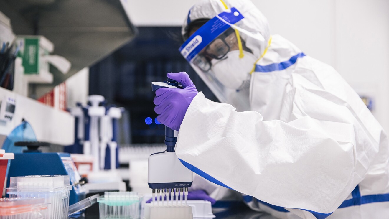 Person in full PPE doing testing in a laboratory setting