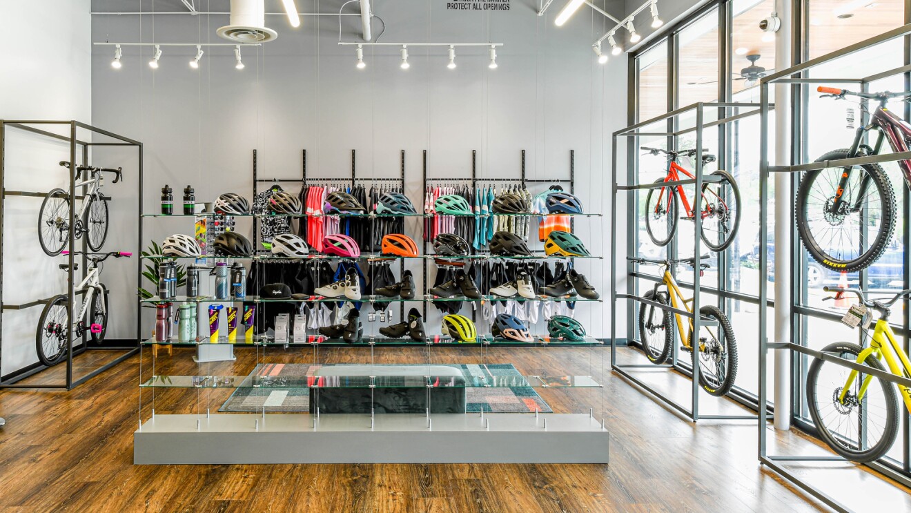 A photo of the inside of Conte's Bike Shop which displays six bicycles, helmets, bike shoes, water bottles and clothing. 