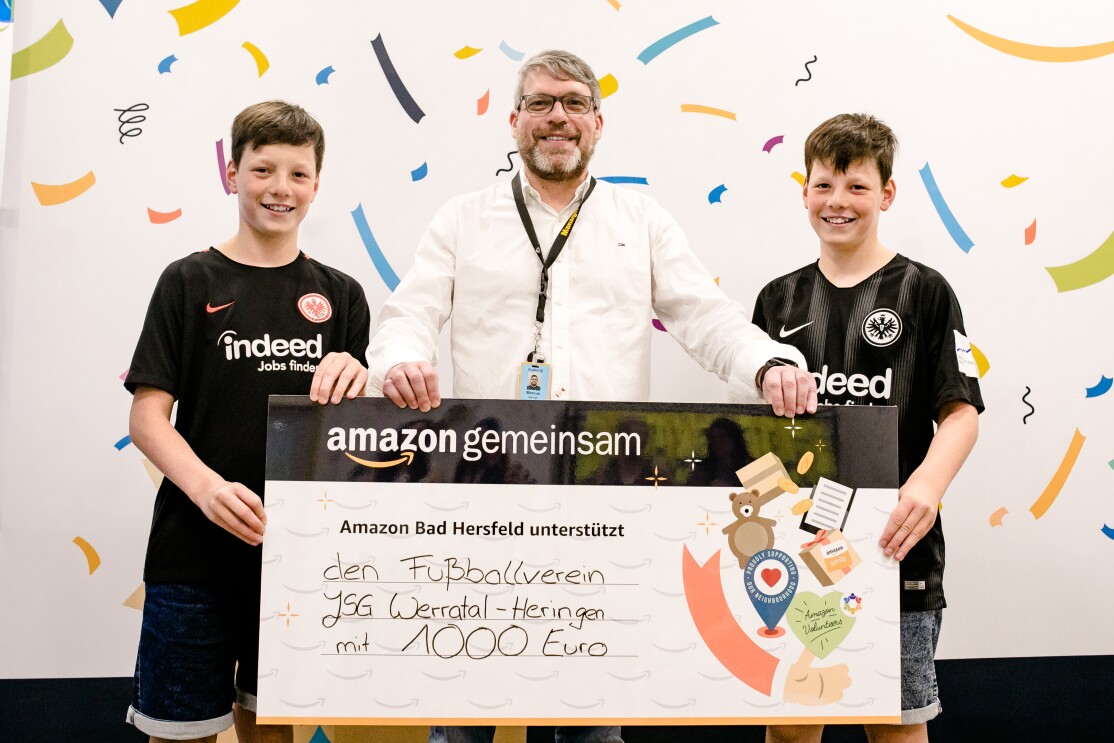Ein Mann (Bildmitte) hält mit den Zwillingen den Spendenscheck