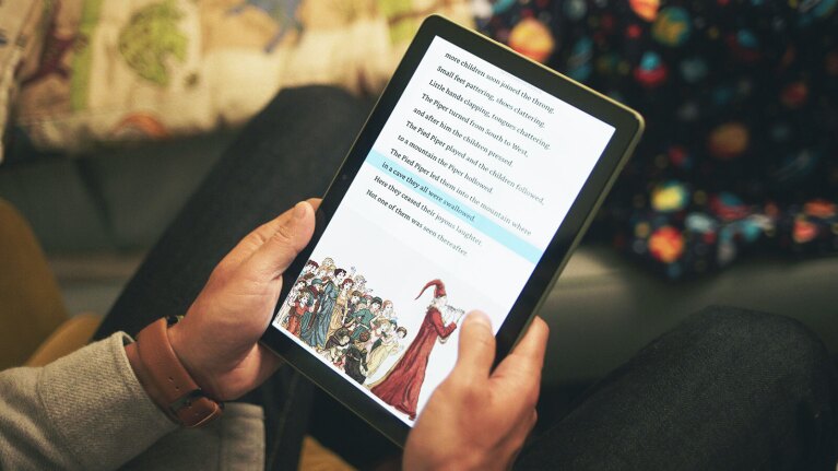 Hands holding a Fire tablet HD 10 displaying a page from the Pied Piper with Reading Ruler turned on.