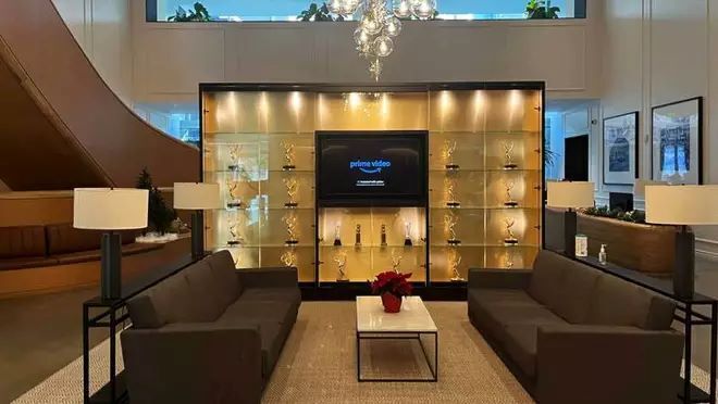 数個のトロフィーがガラスの棚の中に置かれている。その手前に大きなソファーが向かい合わせに置かれている