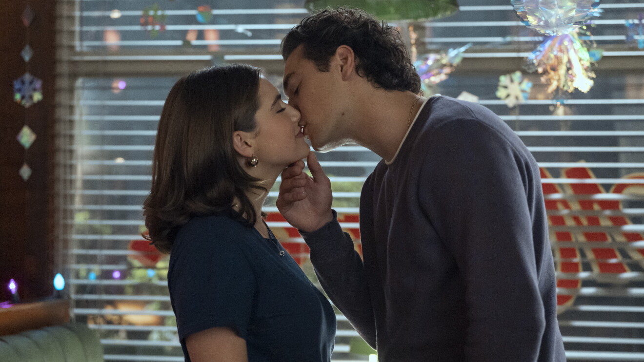 'Off Campus' Couple sharing intimate kiss in front of window with holiday decorations