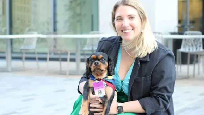 金髪の女性がキャバリア犬を抱いて微笑んでいる。