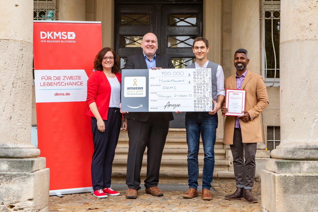 Vier Personen der DKMS nehmen einen Check in Höhe von 100.000€ entgegen.