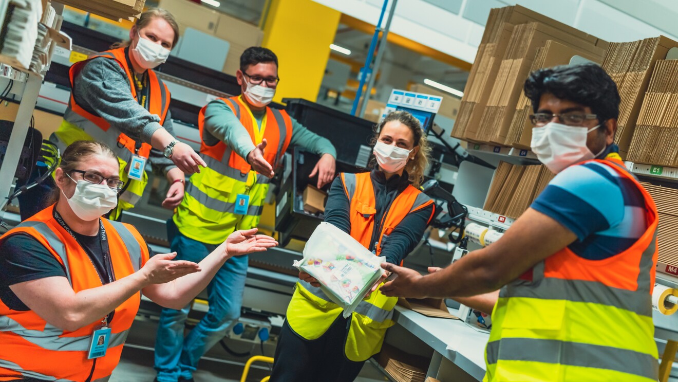 Mitarbeiterin im Logistikzentrum. Sie hält eine Amazon Pakettasche in der Hand.