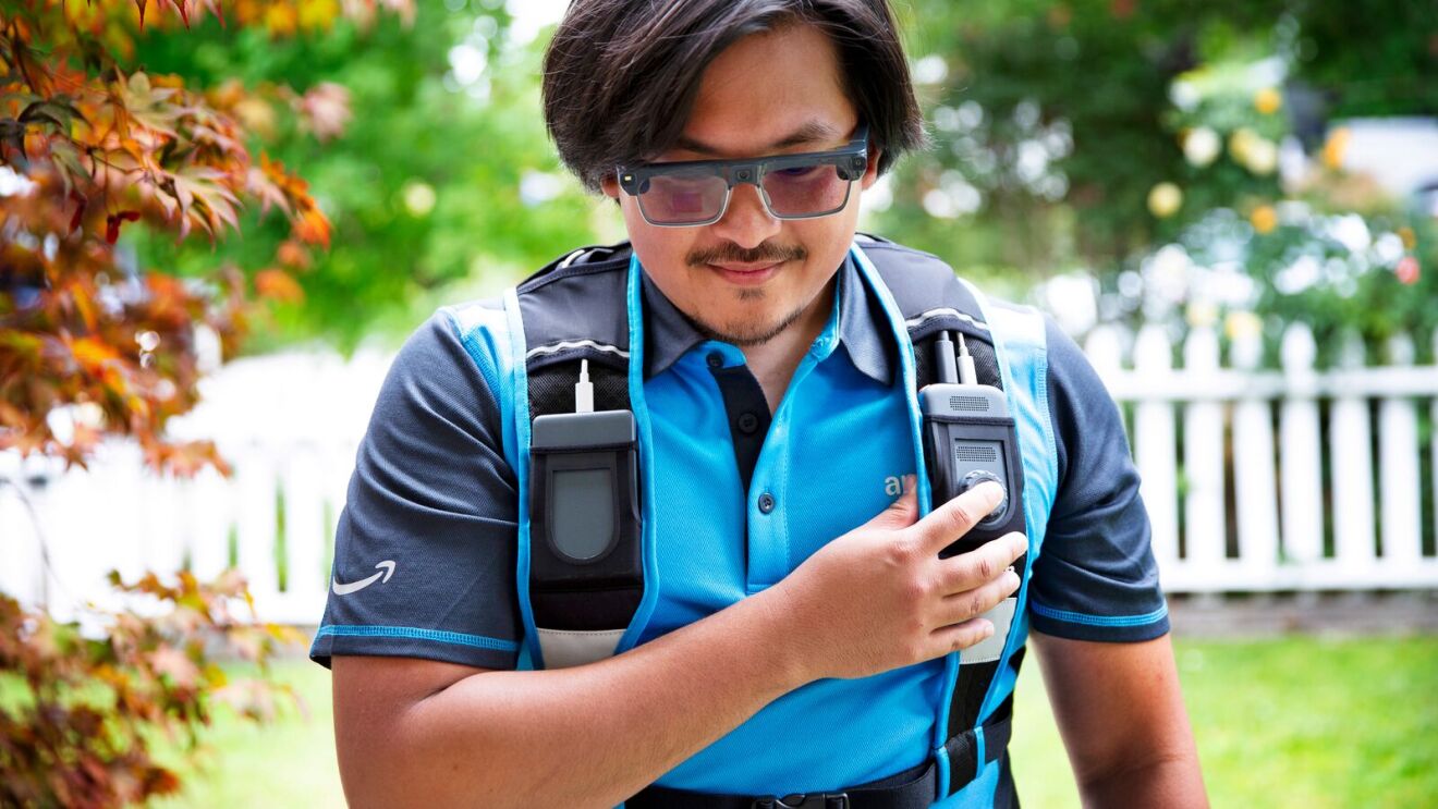 Amazon delivery worker in blue shirt with wearable technology and handheld scanner