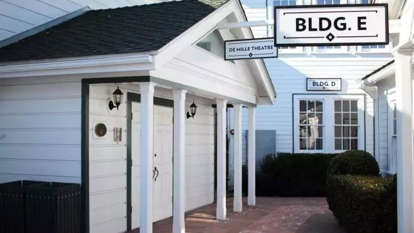 「Demile Theatre」と書かれた看板のかかる白い建物は、黒い屋根が立っている。