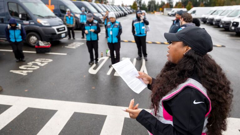 Amazon Delivery Service Partner addressing group of workers in blue vests in parking lot