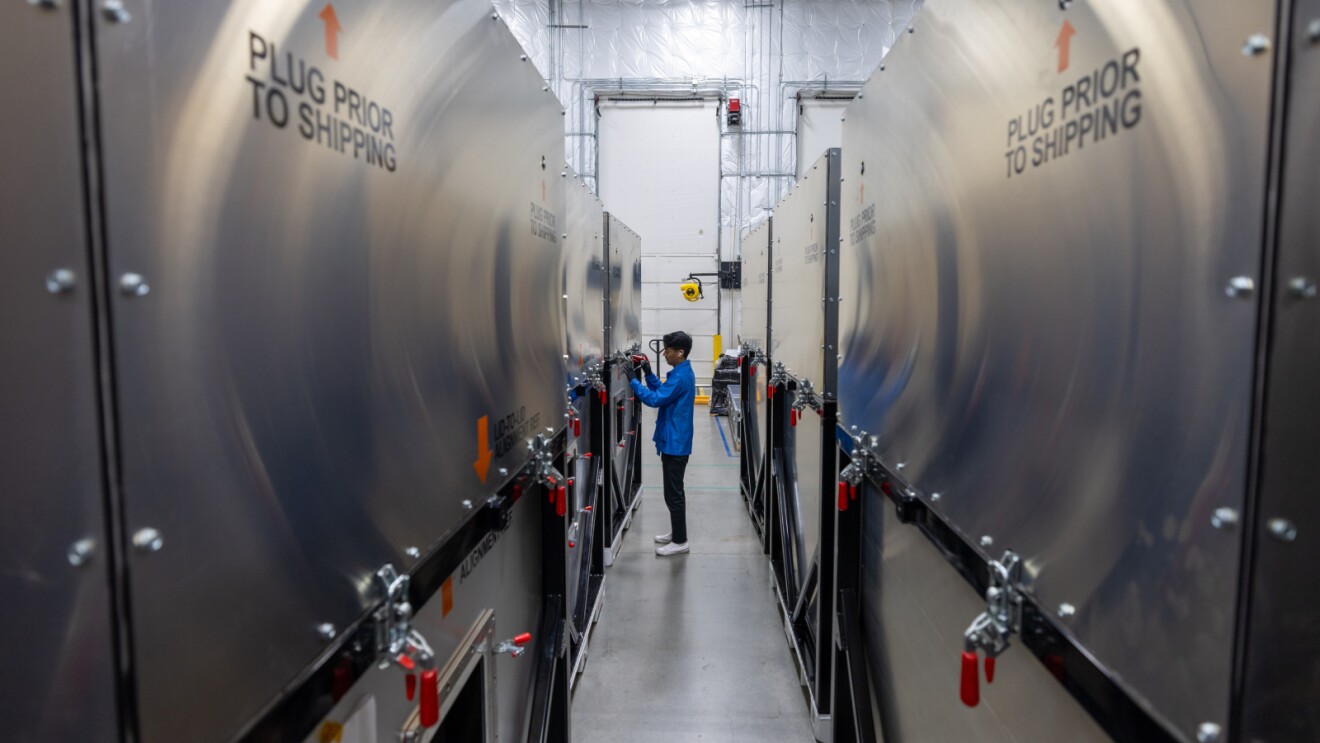 Worker inspecting large industrial equipment labeled 'Plug Prior to Shipping'