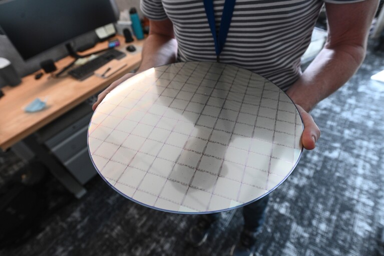 A person holds a large, circular board with a square grid etched on the top of it.