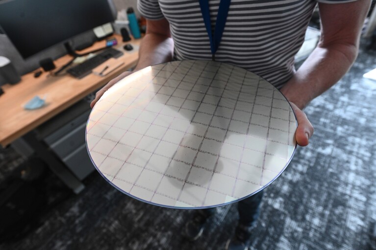 A person holds a large, circular board with a square grid etched on the top of it. 