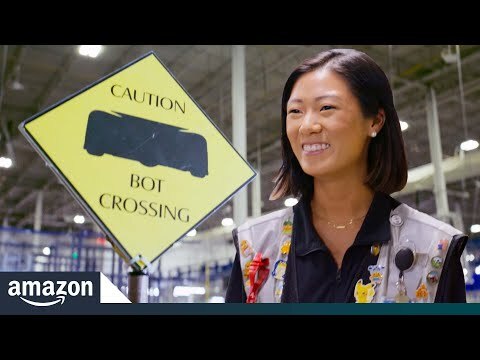 A photo of an Amazon employee working on a robot in a warehouse.