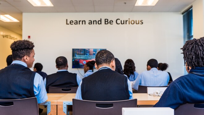 从后面看,在俄亥俄州埃特纳的亚马逊物流中心,学生们坐在教室里的门桌前。