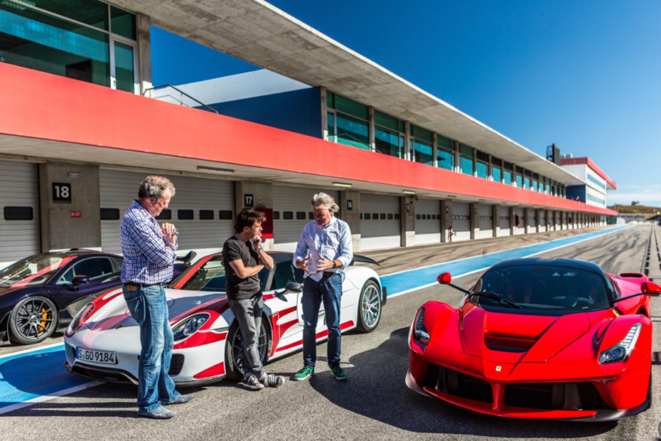 Jeremy Clarkson, Richard Hammond and James May stand next to three sports cars on a race track