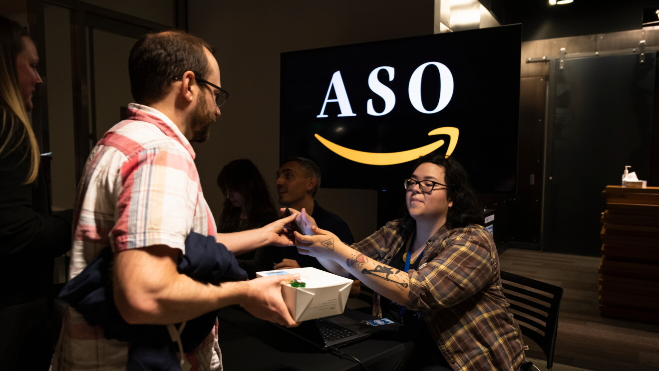 Bileterka sprawdzająca wejściówkę mężczyzny na kocnert. W tle logo Orkiestry Symfonicznej Amazon