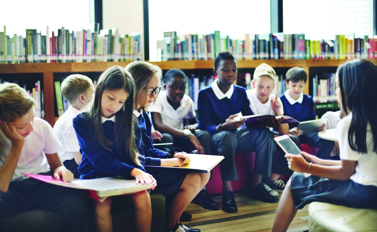 A group of children in a classroom reading 