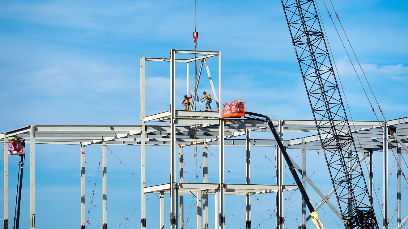 Construction workers on steel frame of new building with crane of an Amazon Data center