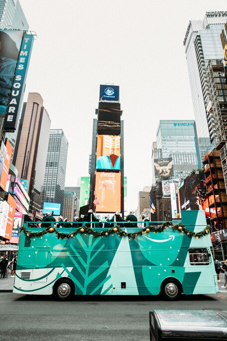 An image of the Harlem Gospel Choir on top of a green double-decker bus singing to crowds in New York.