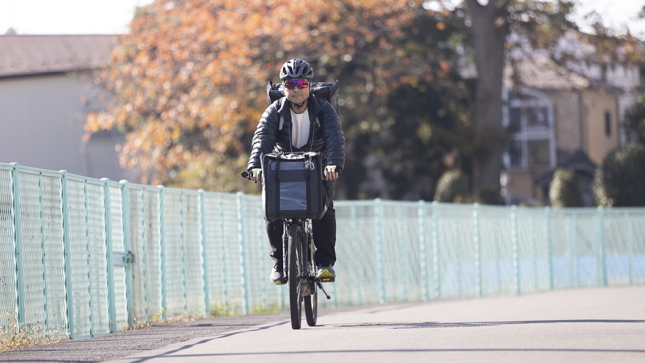 ヘルメットをかぶり自転車に乗って荷物を運ぶ男性