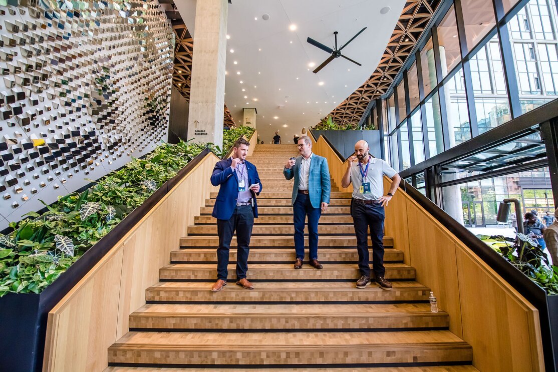 An image of three men standing on the stairs in the Lobby of Amazon HQ2