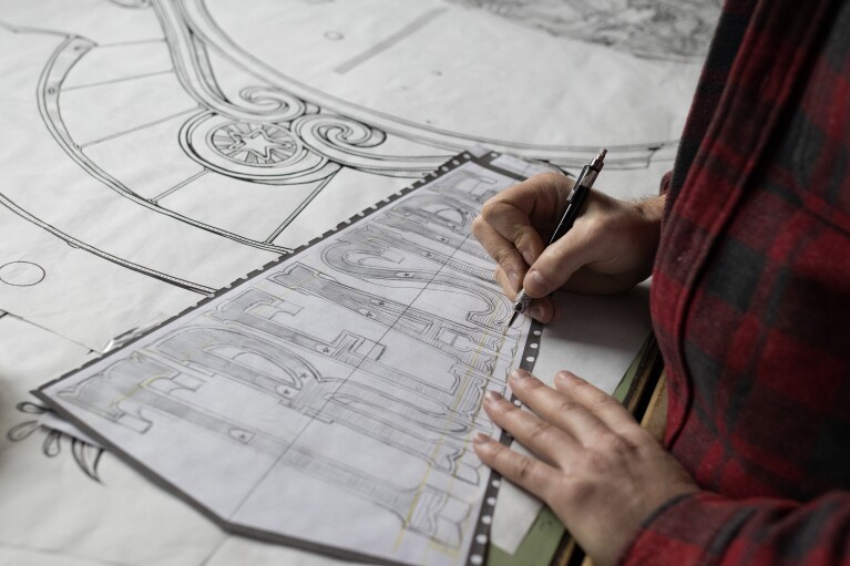 Kyler Martz in his Seattle studio. He is drawing the word TREASURE onto a large piece of paper.