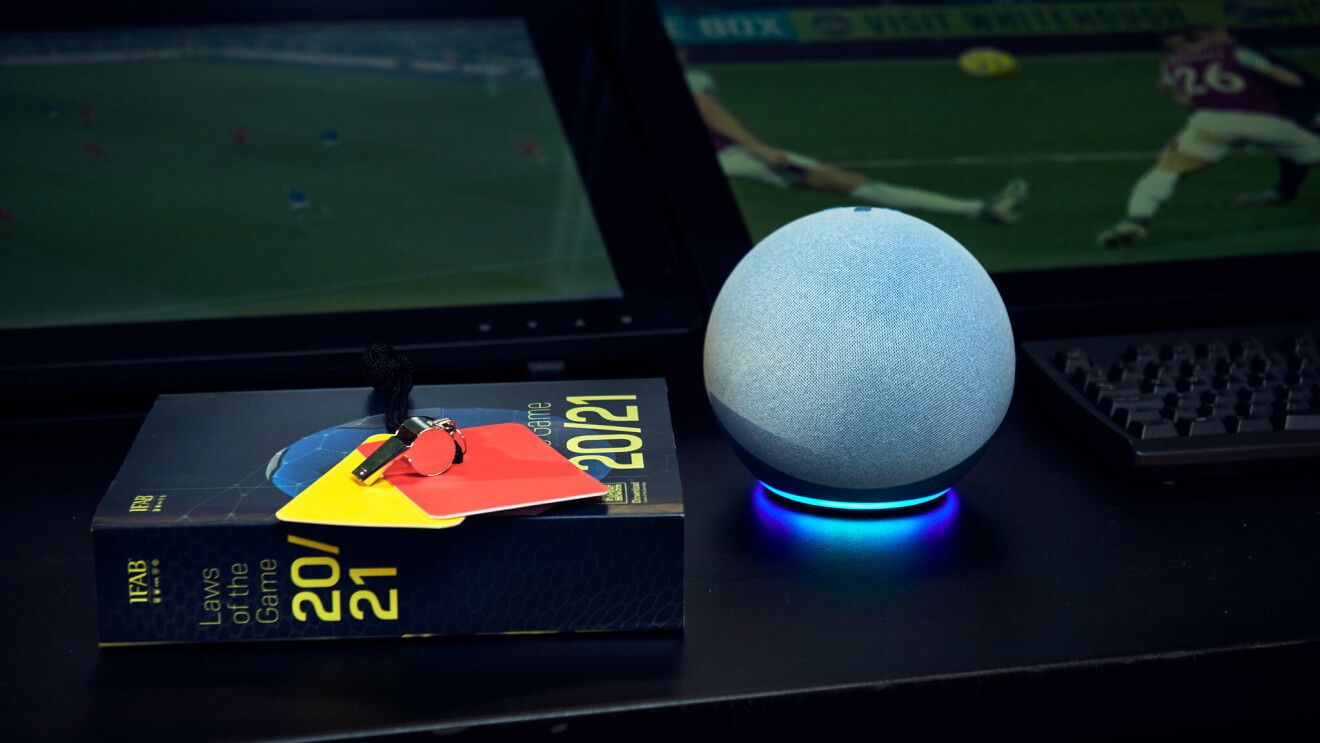 The Echo Dot on a table with a book of football rules and a red and yellow card